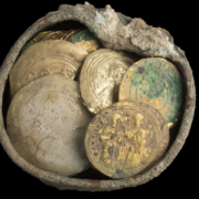 A treasure trove of 24 gold coins and a gold earring discovered in a well-hidden bronze pot during ongoing excavation and conservation work in the ancient harbor of Caesarea. Found among the hoard of Fatimid dinars are six extremely rare 11th century Byzantine coins. Photo © Israel Antiquities Authority.